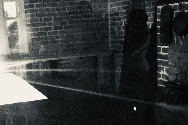 a man standing in front of a brick wall