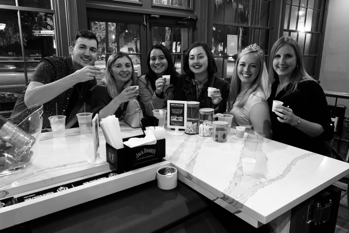 a group of people sitting at a table with a cake